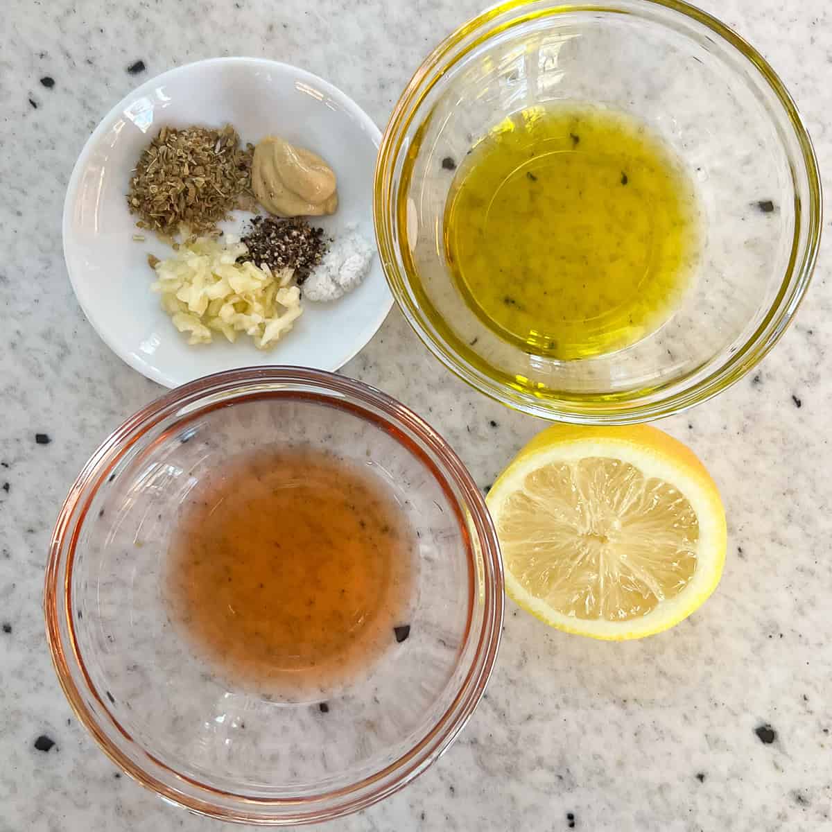 Ingredients for the Greek salad dressing: red wine vinegar, olive oil, lemon, garlic, and seasonings.