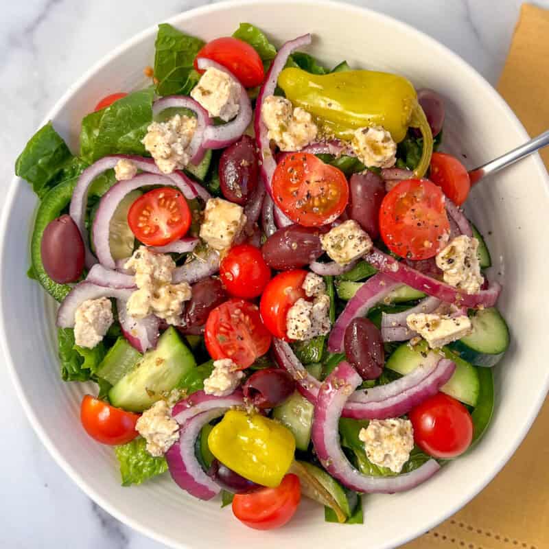 Vegan Greek salad in a bowl with fork.