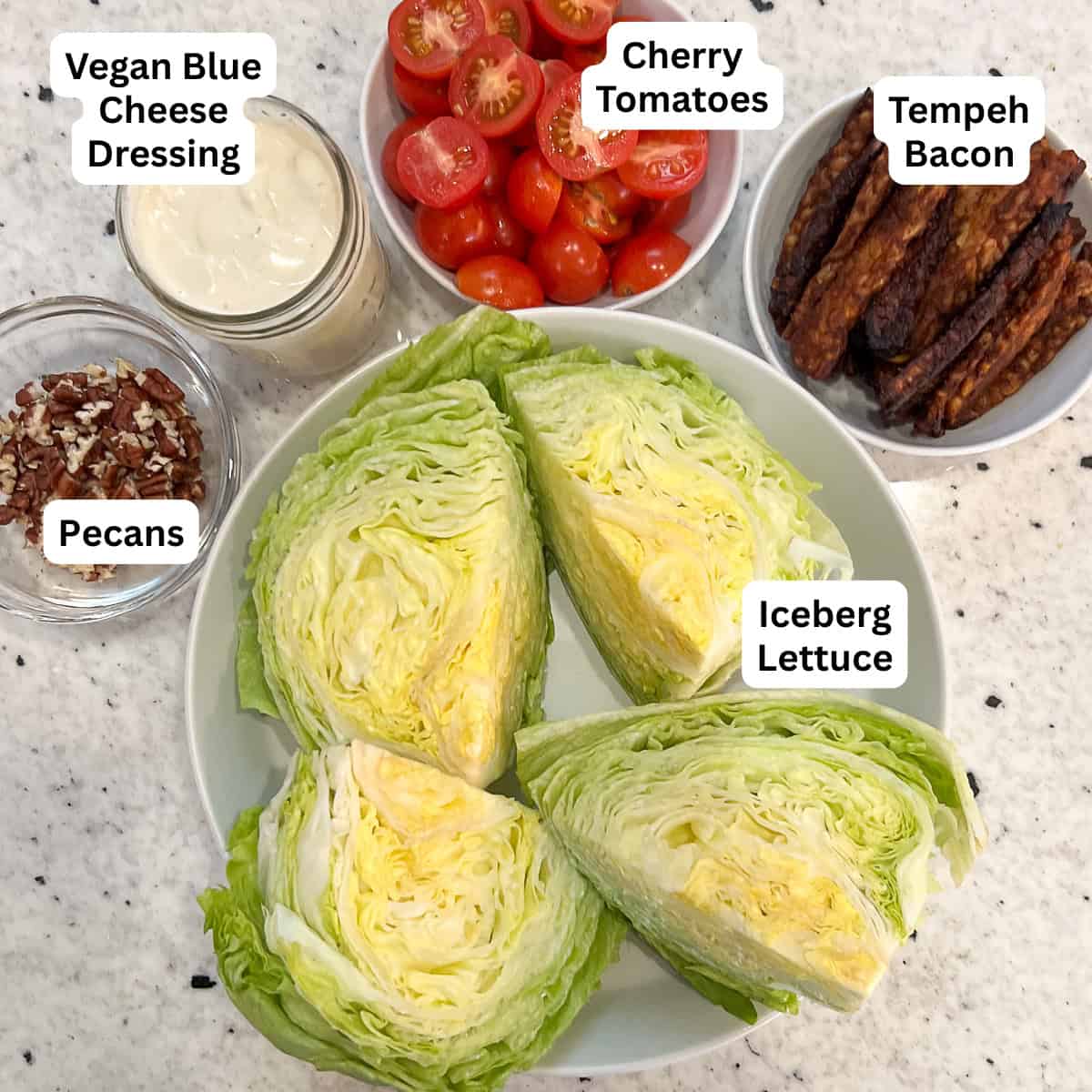 Ingredients for vegan wedge salad: iceberg lettuce, tempeh bacon, tomatoes, vegan blue cheese, and chopped pecans.