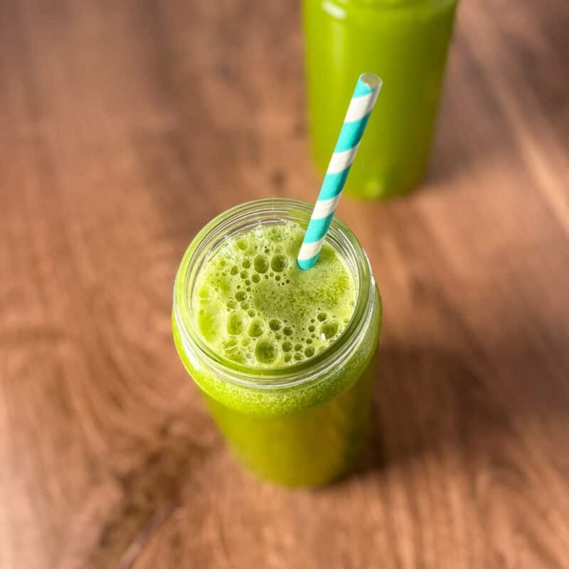 Pineapple cucumber ginger juice in a glass with straw.