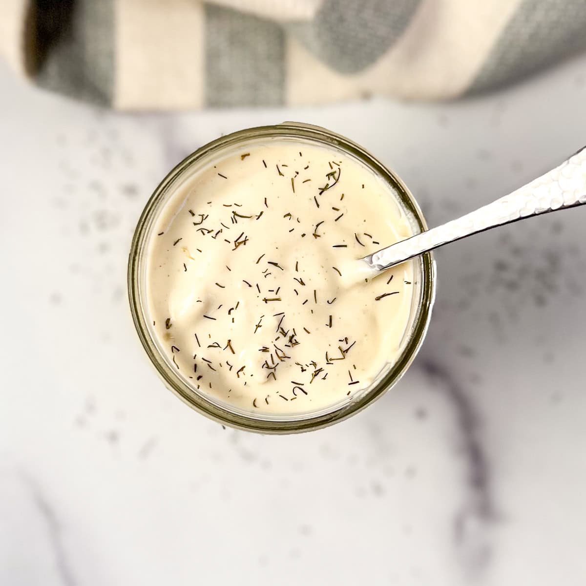 Vegan blue cheese dressing in a mason jar with a sprinkle of dried dill on top.