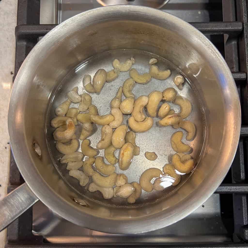 Cashews in a pot with water on the stovetop.