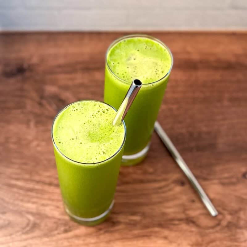 Two glasses of celery apple parsley ginger juice with metal straws.