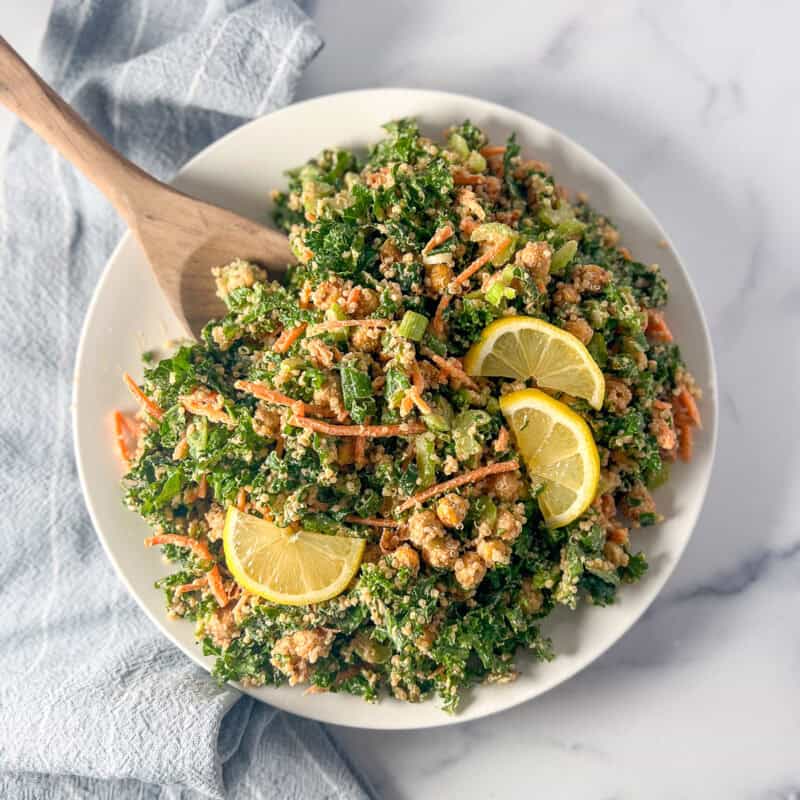 Kale and quinoa salad in a bowl topped with fresh sliced lemon.