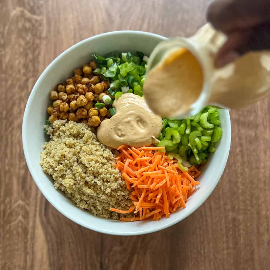 Chipotle cream sauce being drizzled over the kale and quinoa salad.