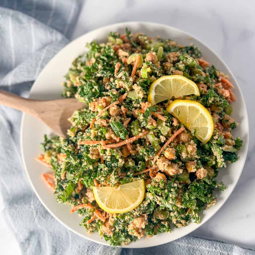 Kale and quinoa salad being mixed in a bowl.