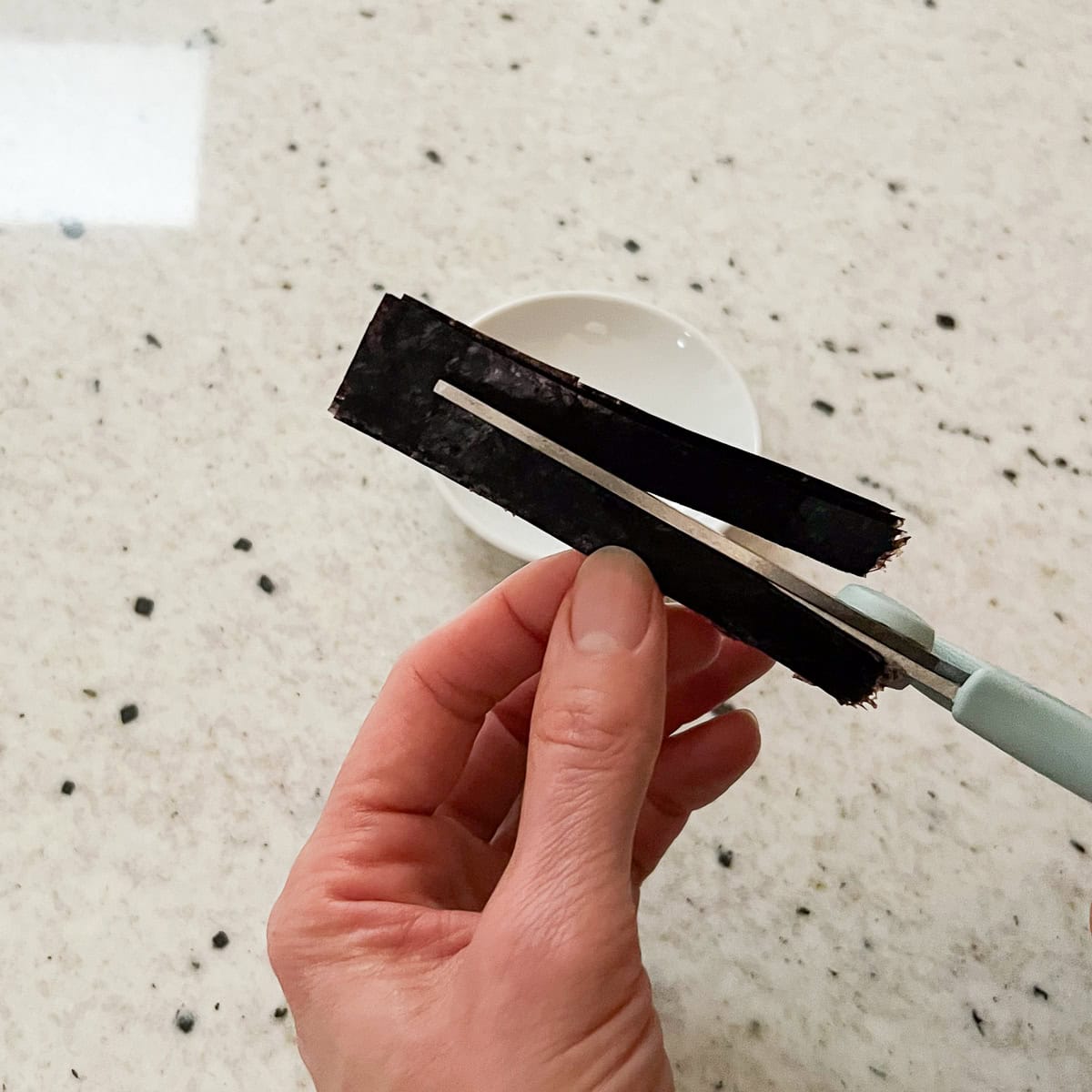 Cutting the nori sheets into thinner strips.