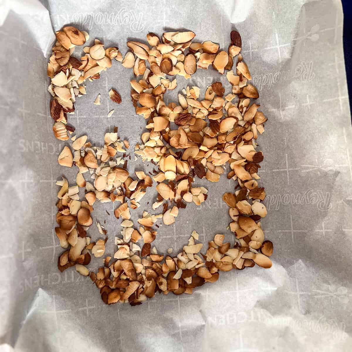 Toasted sliced almonds on a baking sheet for the arugula quinoa salad.