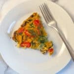 A slice of crustless vegan quiche on a plate with a fork.