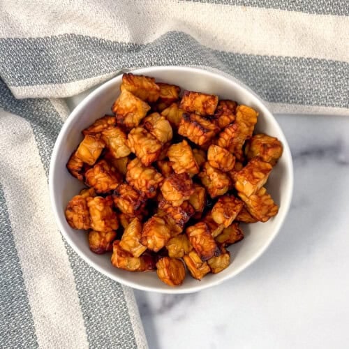 Air fryer tempeh cubes in a bowl, with napkin on the side.