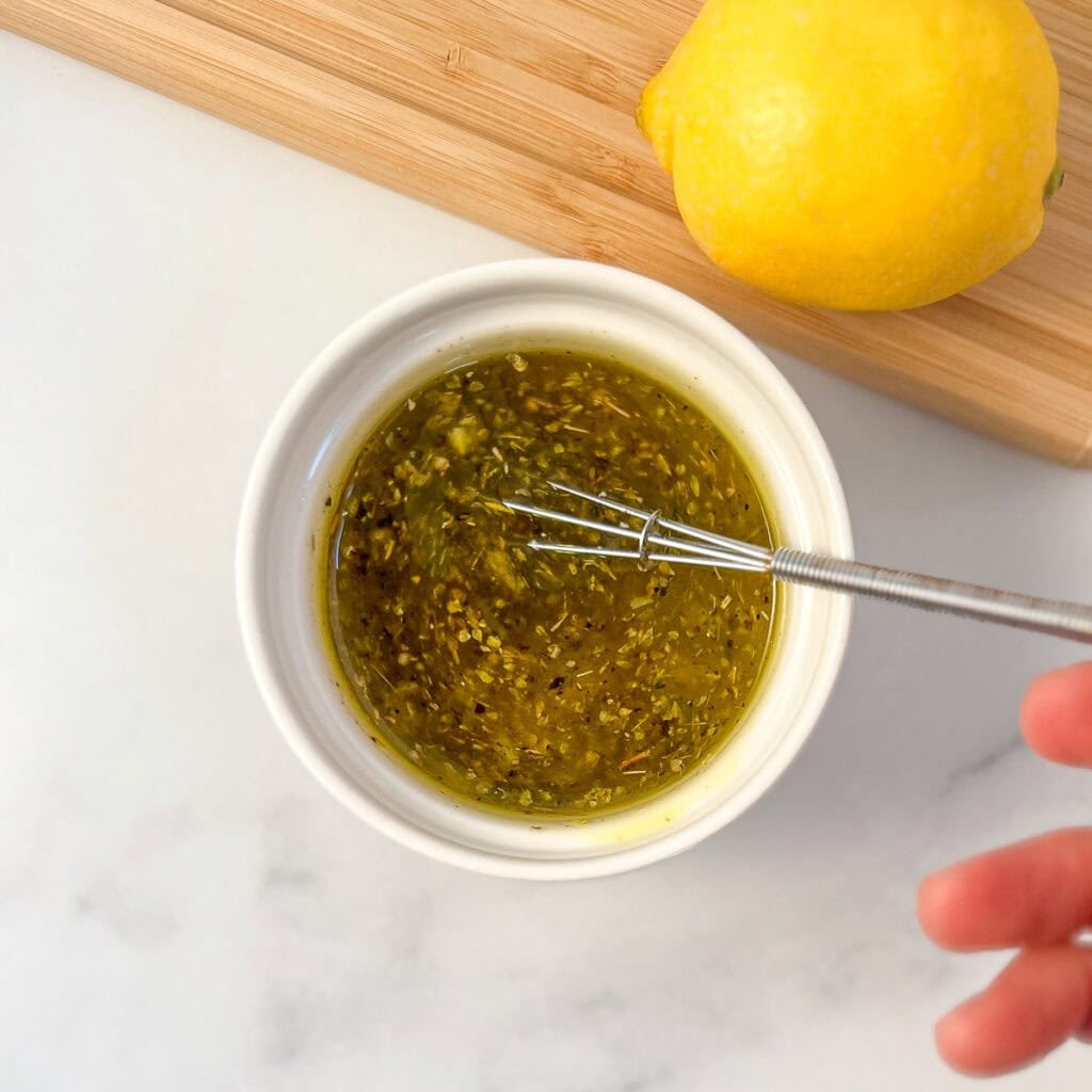 Lemon vinaigrette dressing being whisked in a small bowl.