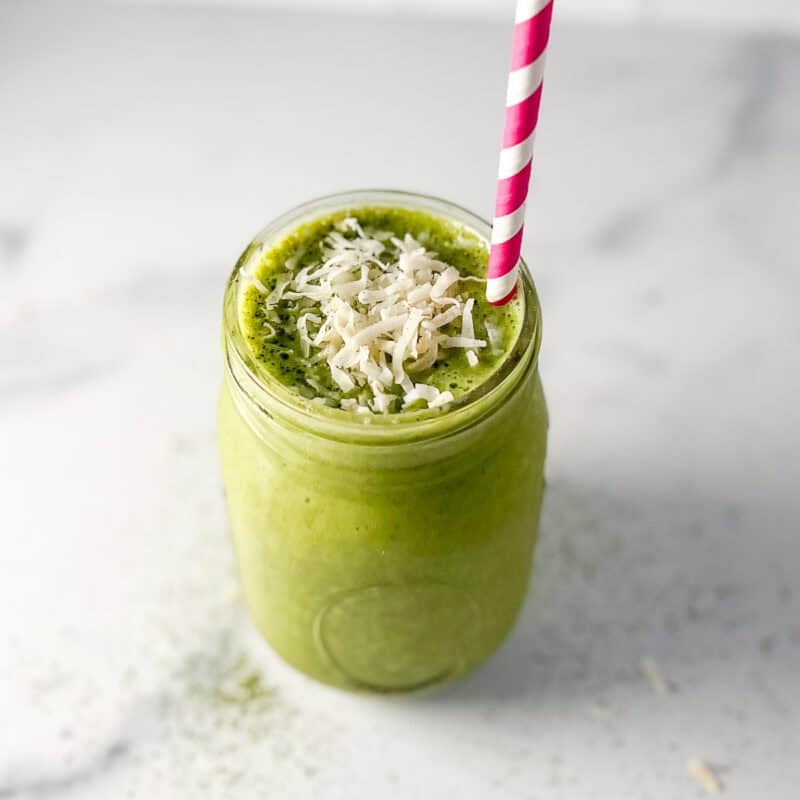 Matcha smoothie in a mason jar with straw.