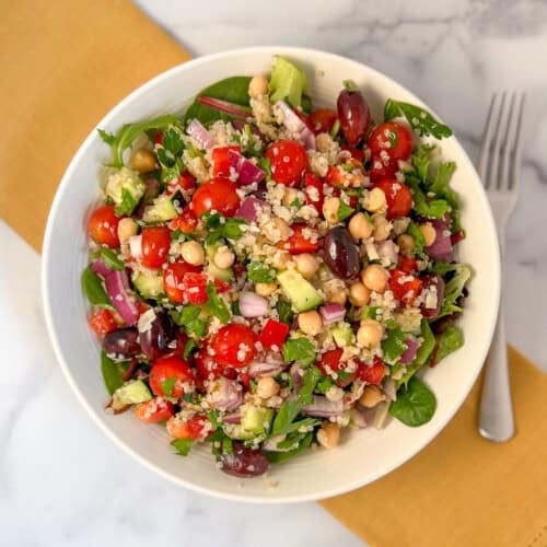 Mediterranean quinoa salad in bowl with fork on the side.