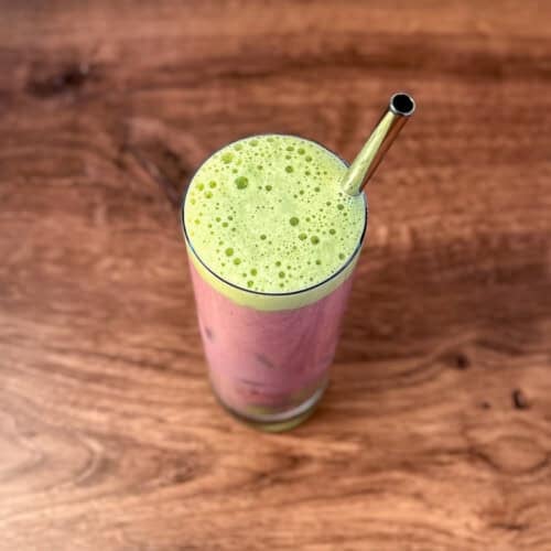 Iced Strawberry Matcha Latte in a tall glass with metal straw.