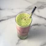 Iced strawberry matcha latte in a tall glass with straw.