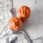 Two sunrise sunset smoothies in mason jar glasses with straws.