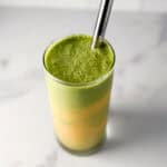 Mango matcha latte in a glass with a straw.