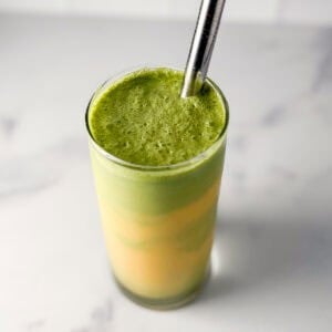 Mango matcha latte in a glass with a straw.