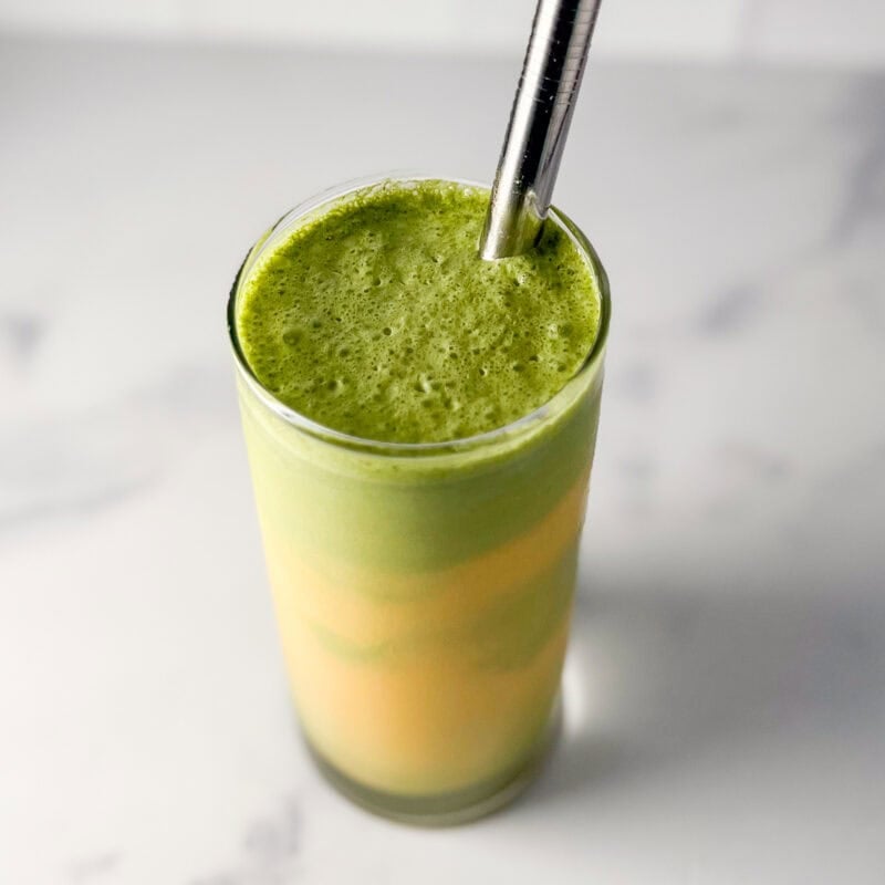 Mango matcha latte in a glass with a straw.