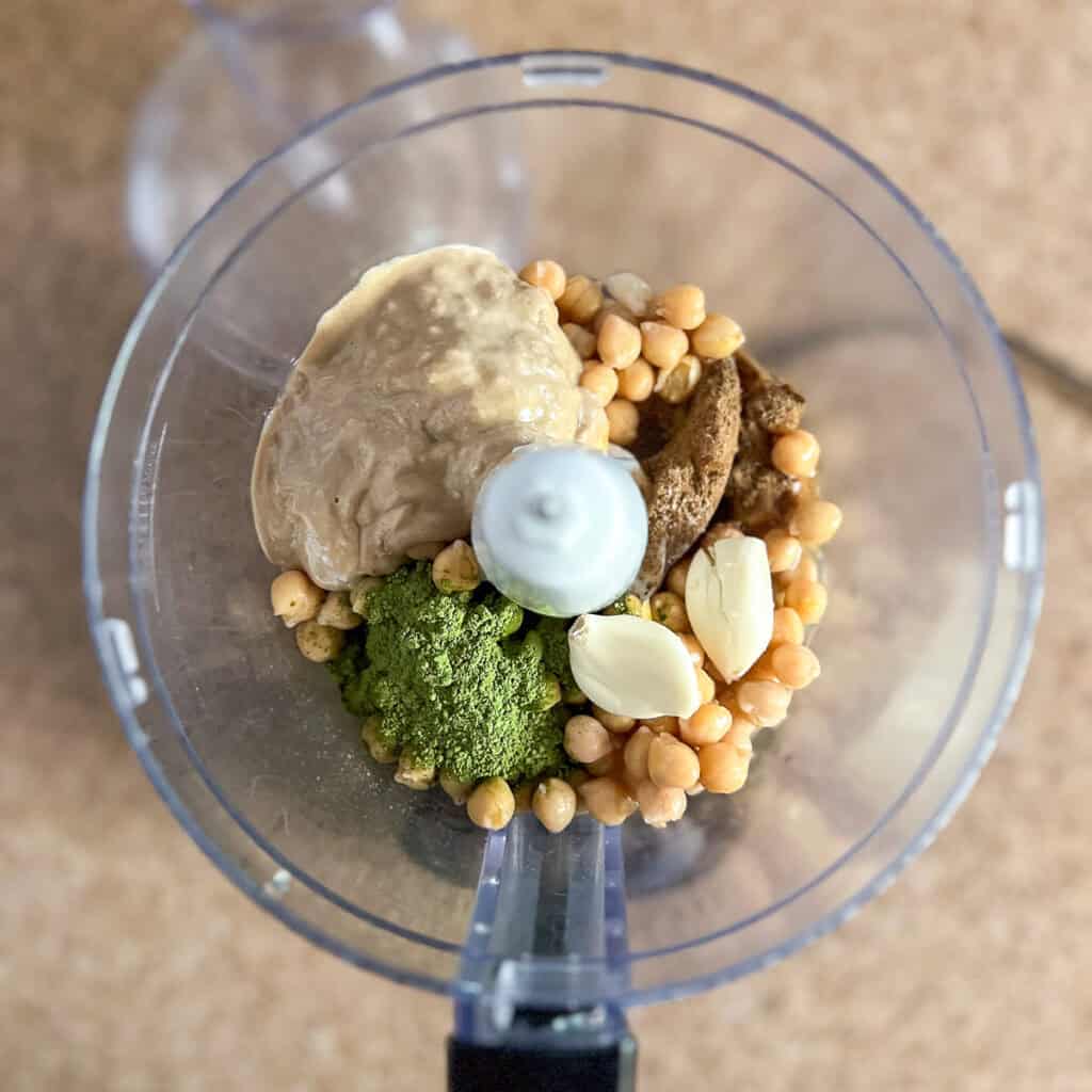 Food processor with ingredients of matcha hummus.