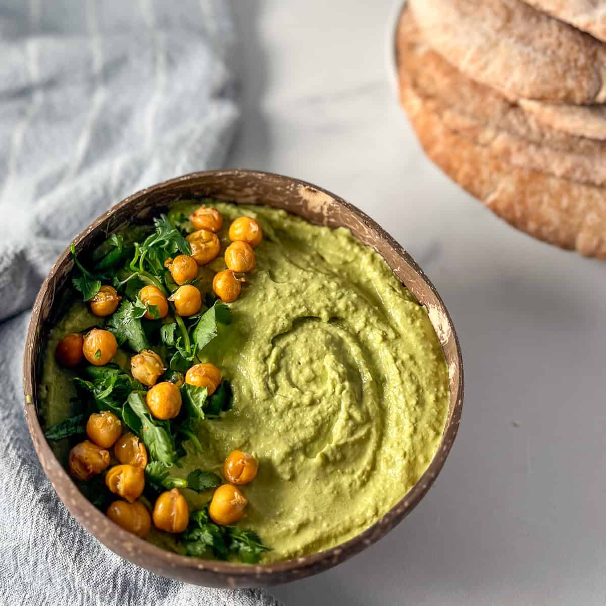 bowl of matcha hummus topped with cilantro and roasted chickpeas