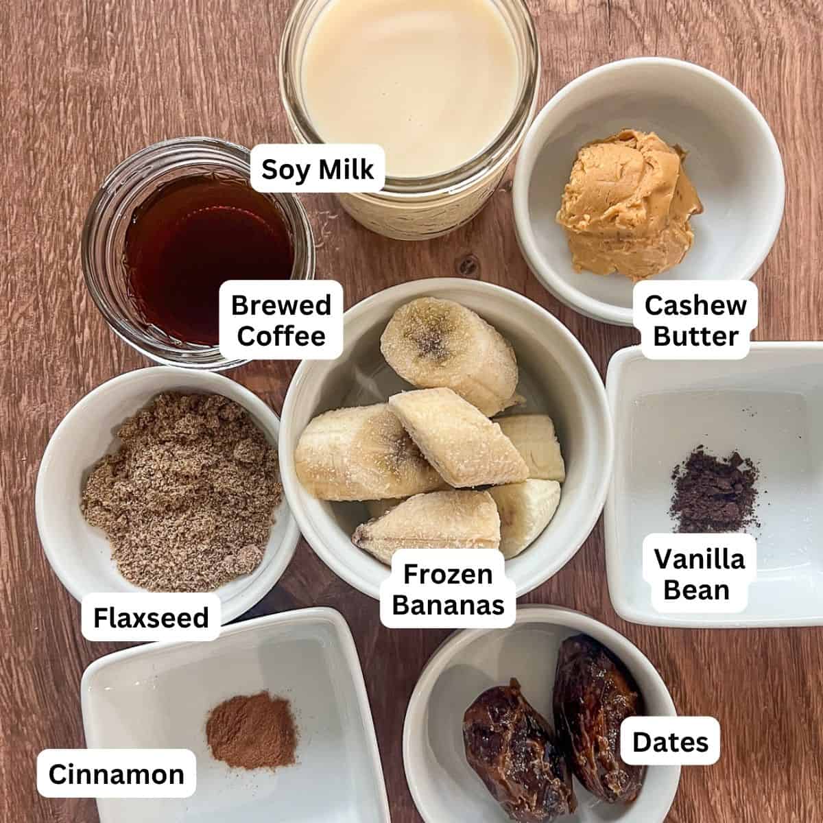 Bowls with ingredient listed of bananas, soy milk, vanilla bean, cinnamon, dates, brewed coffee and flaxseed. 