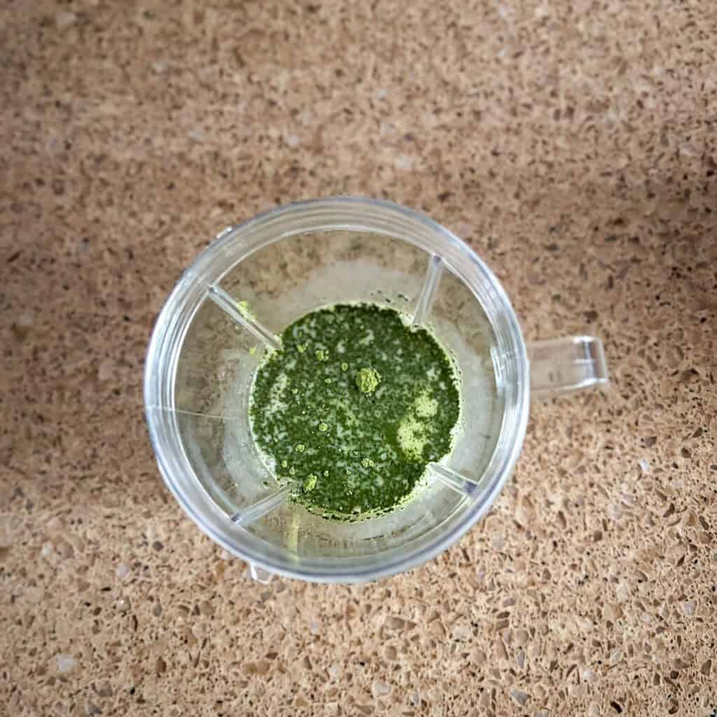 A bullet blender with matcha powder and plant based milk.