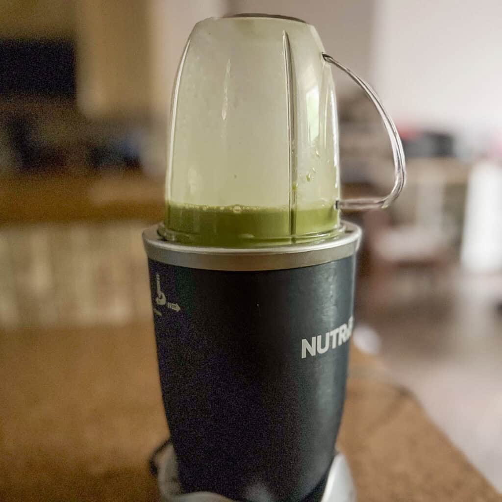A bullet blender with blended plant based milk and matcha powder.