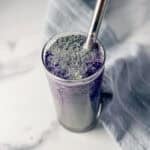 glass of blueberry matcha with a metal straw.