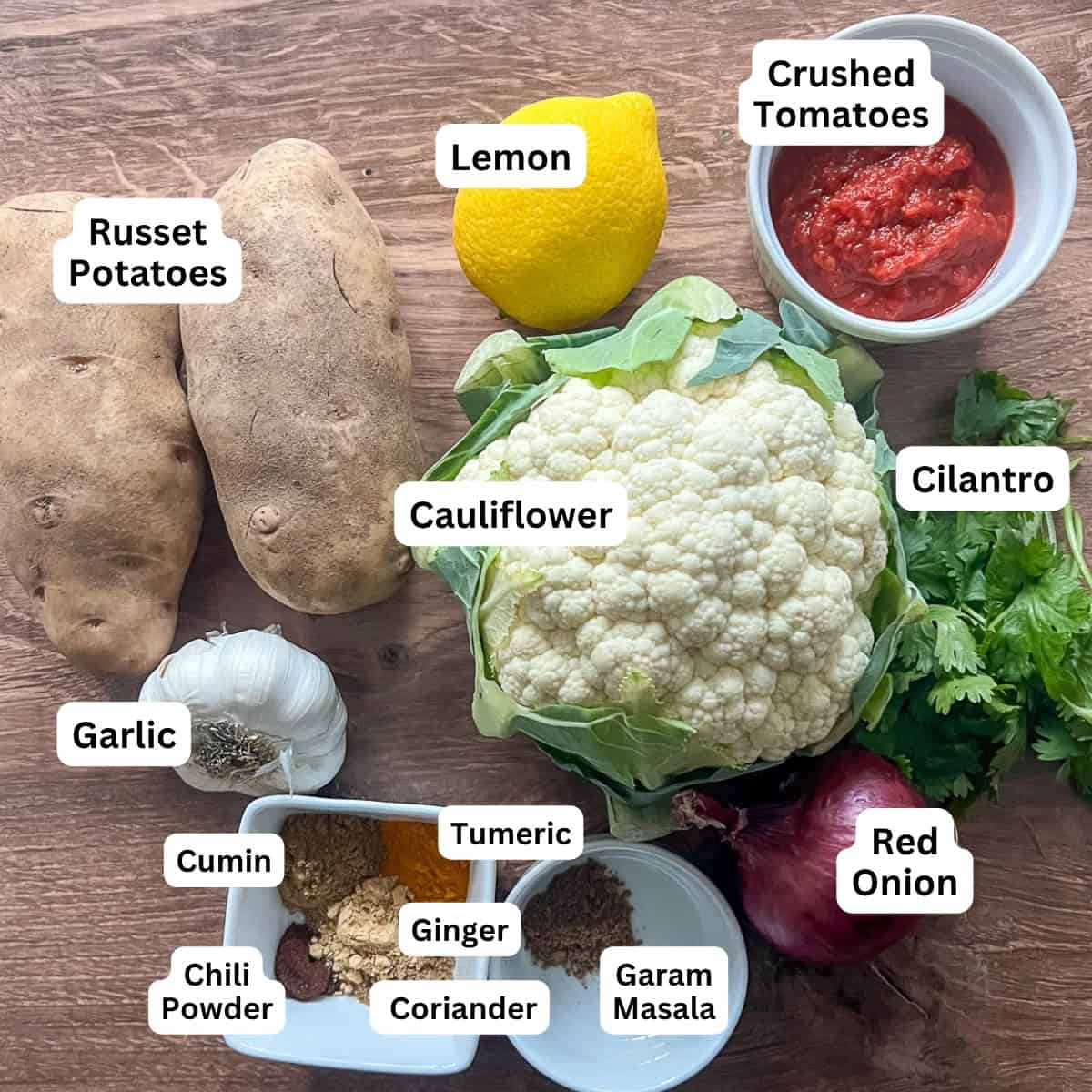 Ingredients for Aloo Gobi: potatoes, lemon, crushed tomatoes, cauliflower, cilantro, garlic, red onion, and spices.