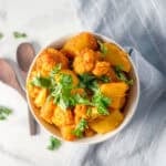 A bowl of potato and cauliflower mixed with herbs and spices.