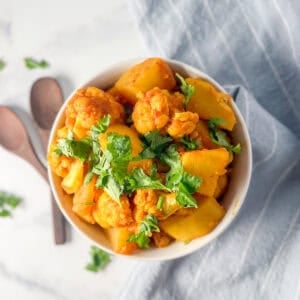 A bowl of potato and cauliflower mixed with herbs and spices.