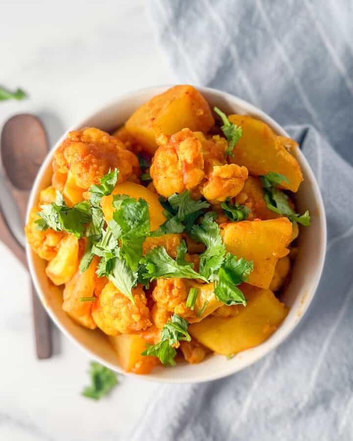 A bowl of potato and cauliflower mixed with herbs and spices.
