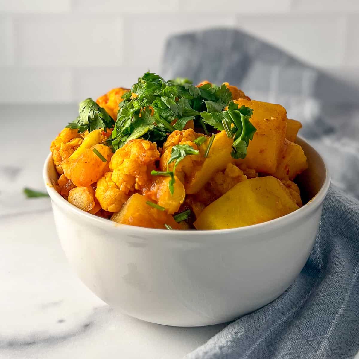 A bowl of aloo gobi topped with fresh cilantro.