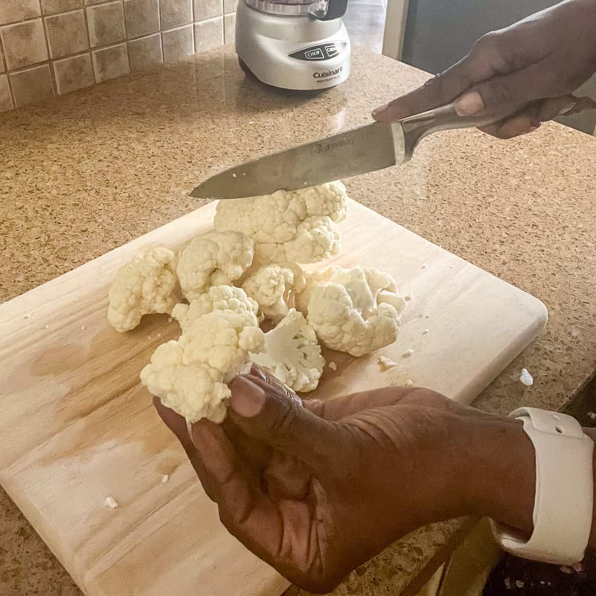 Chopping cauliflower on a cutting board.