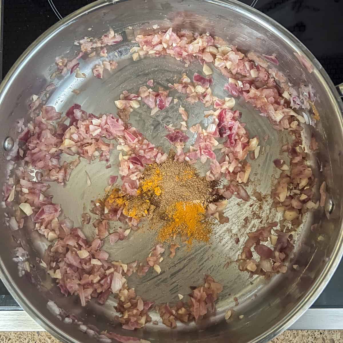 A variety of seasonings in a pan with onions and garlic.