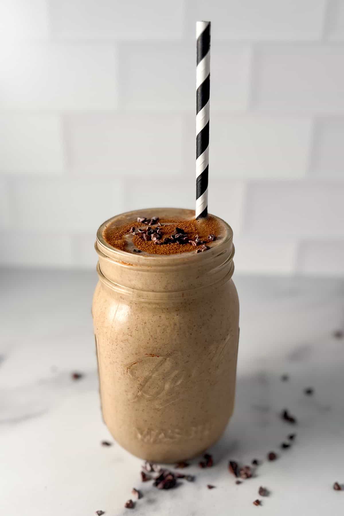A banana smoothie with coffee in a mason jar with straw. 