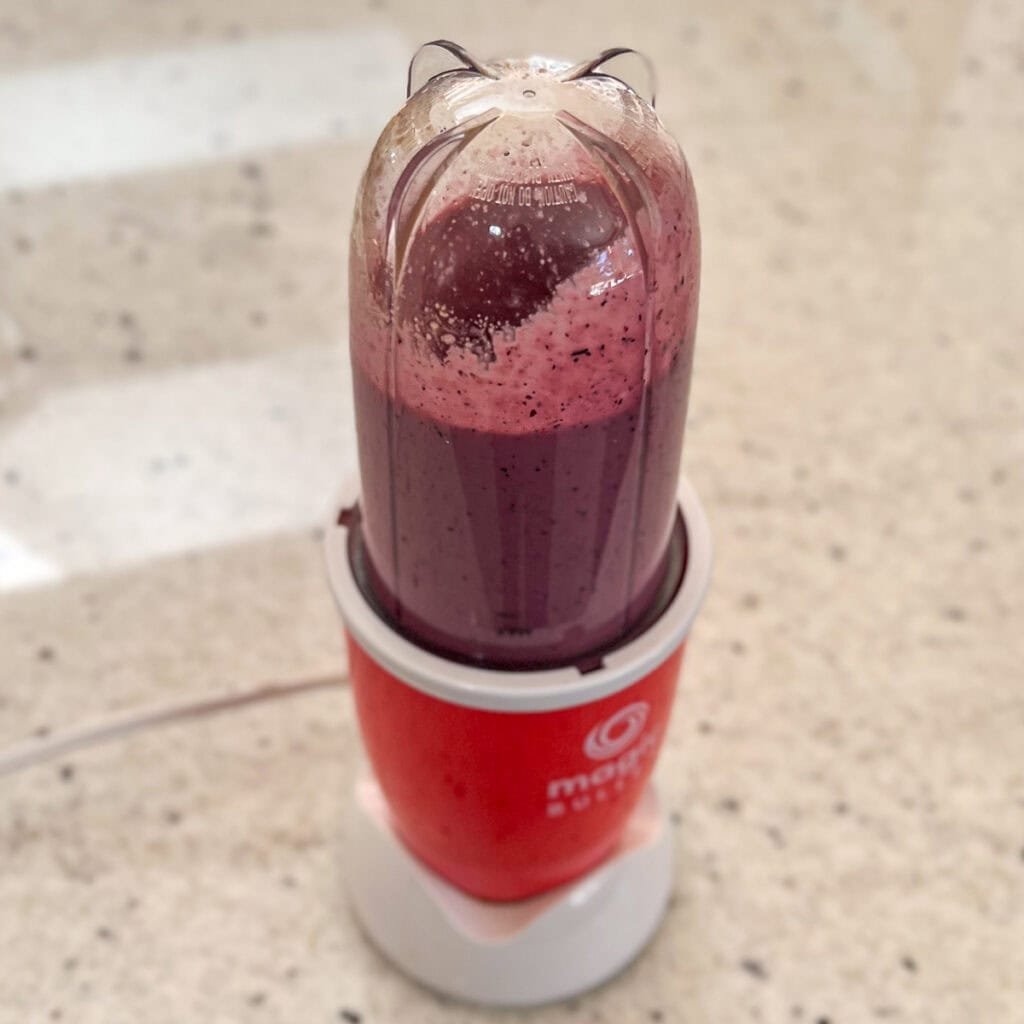 Blueberry vinaigrette dressing being blended in a mini bullet blender.