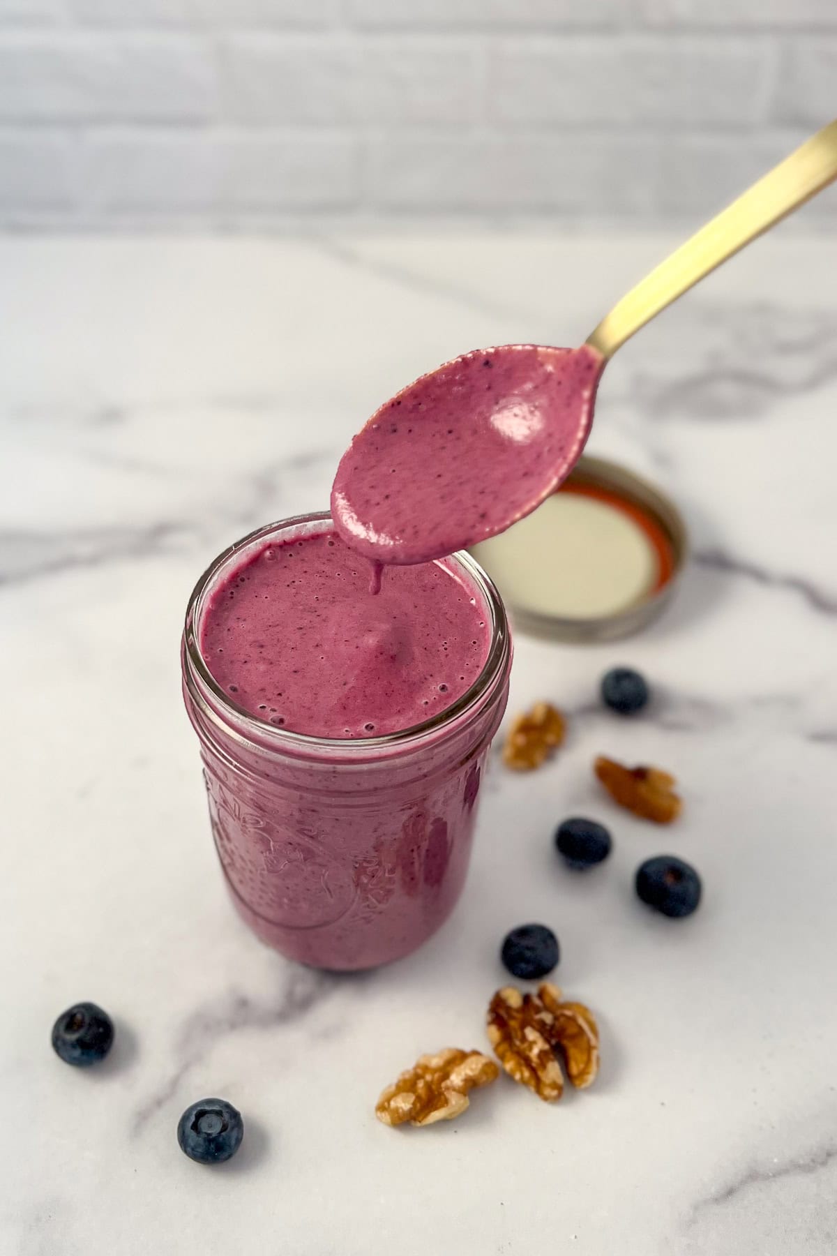 Blueberry vinaigrette dressing in a mason jar with a spoon lifting some out.