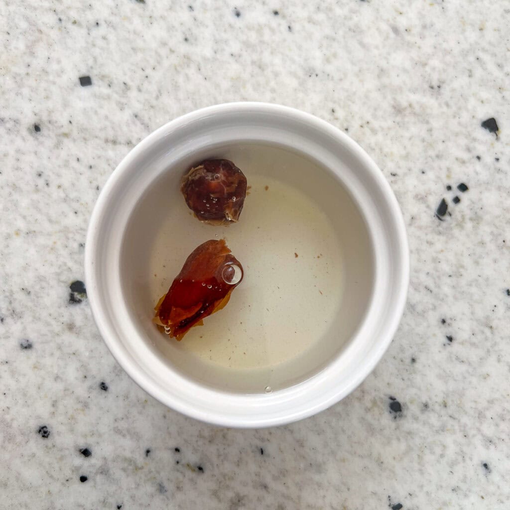 Two pitted dates soaking in boiling hot water.