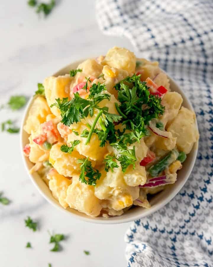 A bowl of potato salad top with parsley.