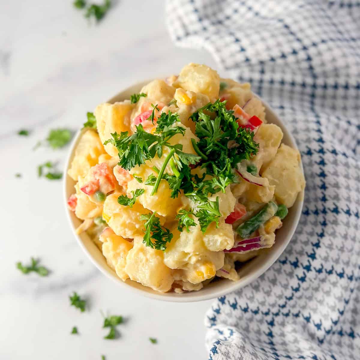 A bowl of potato salad top with parsley.