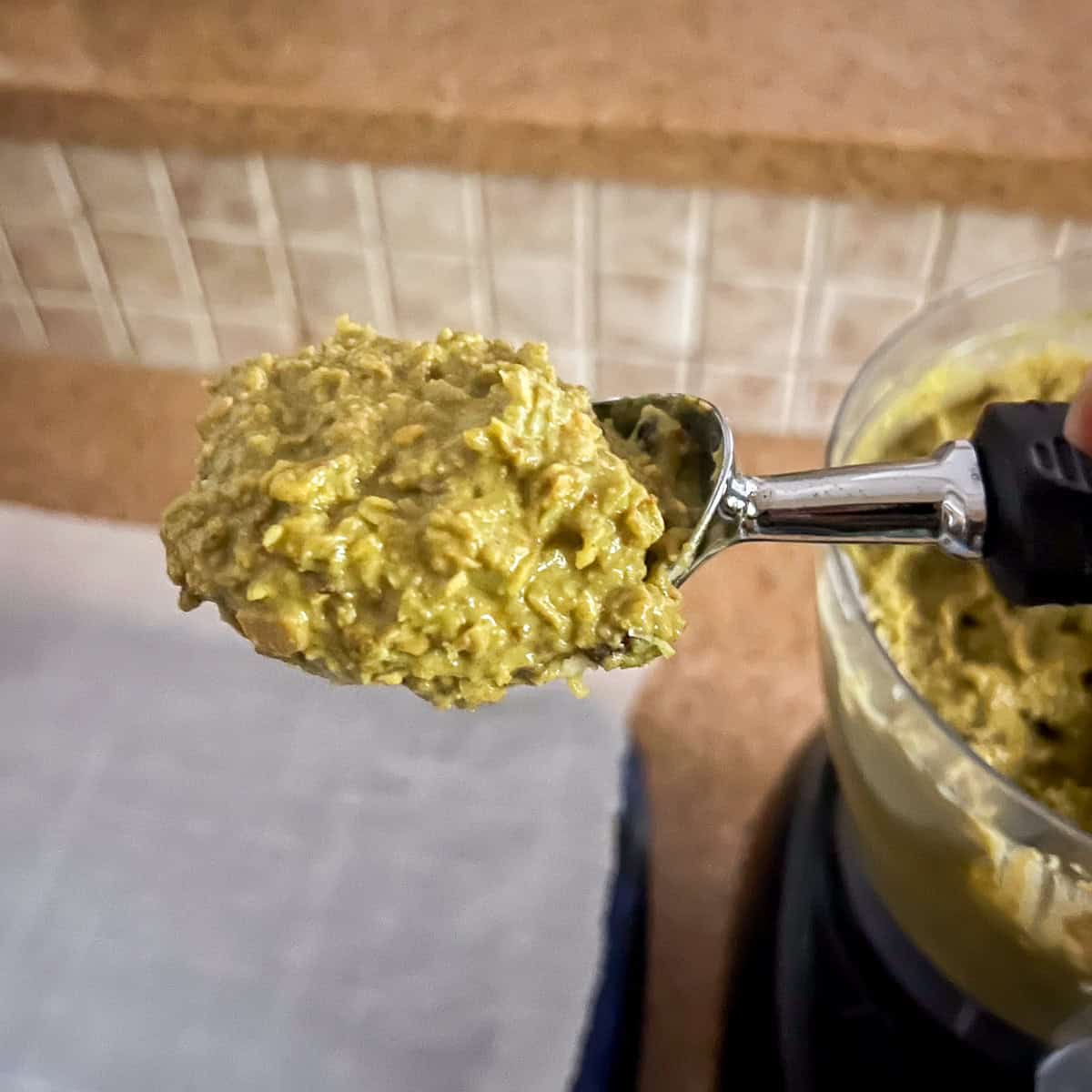 A spoon filled with matcha oatmeal cookie batter.