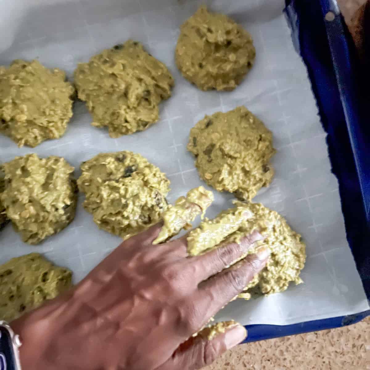 Matcha oatmeal cookies being scooped onto a baking sheet.