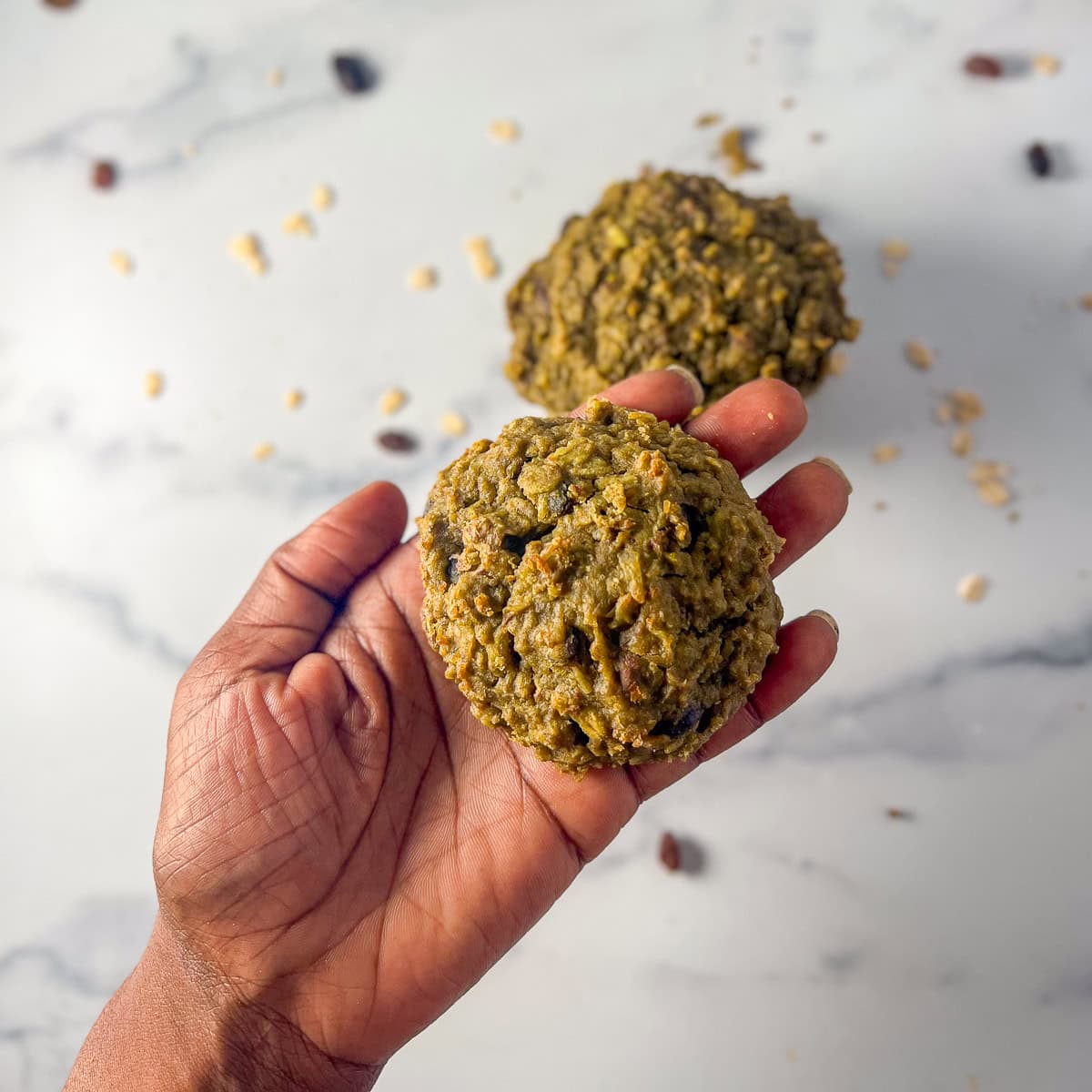 A hand holding a matcha oatmeal cookie.