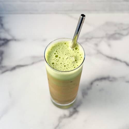 Pumpkin spice matcha latte in a tall glass with a metal straw.