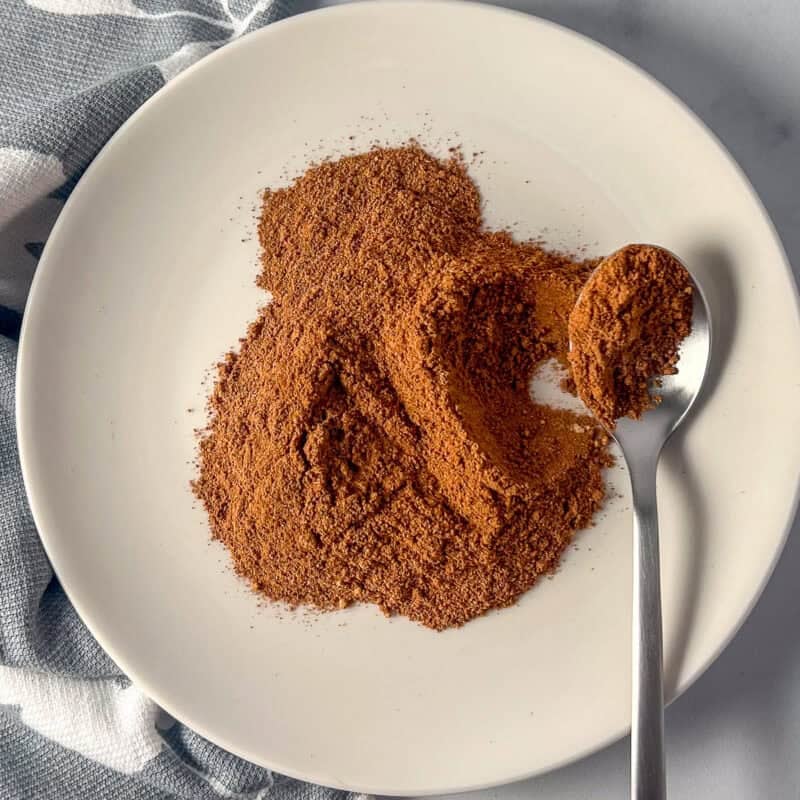 A plate with a spoon filled with pumpkin pie spice mix.