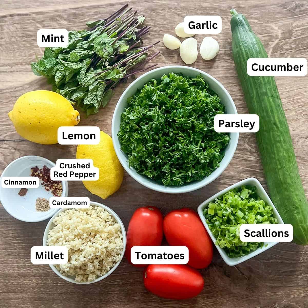 A display of parsley, cucumber, tomatoes, onions, garlic, lemons, mint and seasonings. 