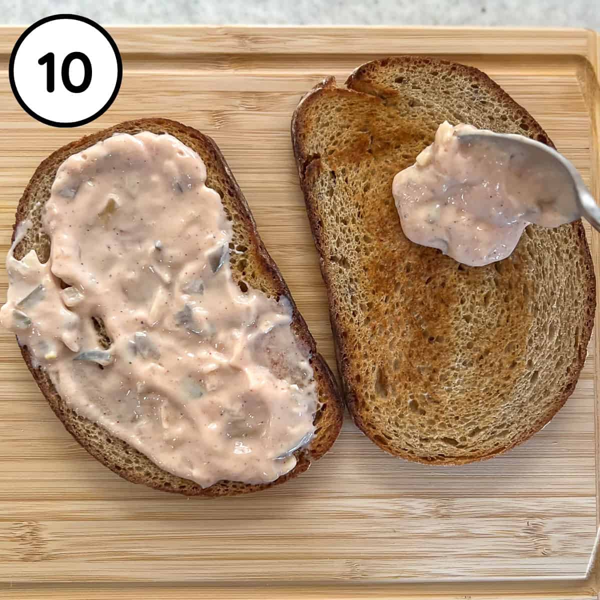 Vegan thousand island dressing being spread over the toasted rye bread.