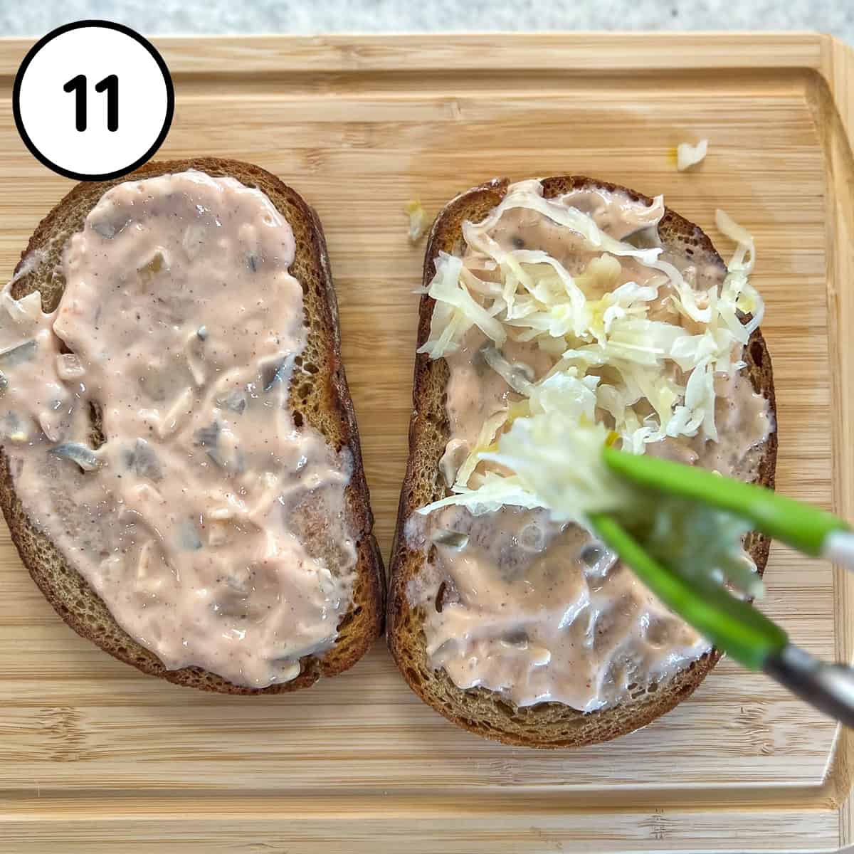 Sauerkraut being added to rye bread with vegan thousand island dressing.